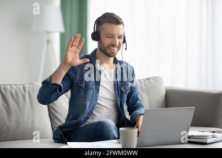 Smiling man having business video conference, using headset and laptop Stock Photo