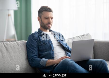 Concentrated man using computer, having part time job at home Stock Photo