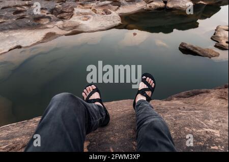 Point of view of Man legs with hiking shoes sitting on rock cliff in grand canyon Stock Photo