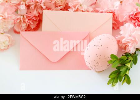 Two envelopes, Easter egg and floral decoration with pink carnations and buxus. Graphic resources Stock Photo
