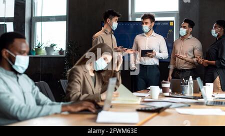 Colleagues in masks having meeting in boardroom, working on project Stock Photo