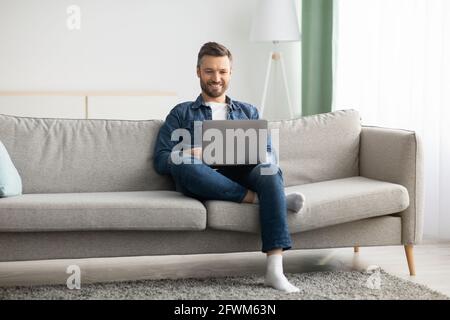 Handsome bearded man using laptop and smiling Stock Photo
