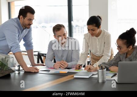 Focused diverse colleagues employees team working with documents together, brainstorming Stock Photo