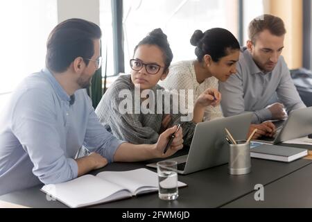 Diverse colleagues employees brainstorming, using laptops, working on project Stock Photo