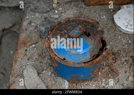 Old rusty blue cooking pot, left in ruined stone building. Heavily decayed with parts of metal eaten away by rust. Isolated on stone background. Stock Photo