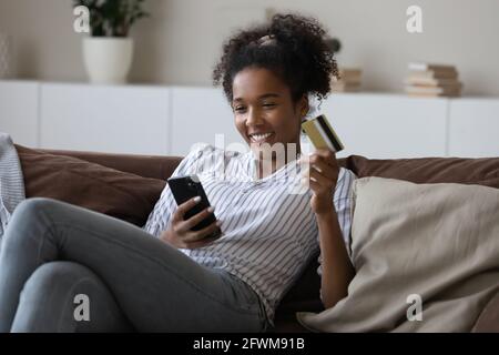 Happy beautiful young african woman shopping in mobile application. Stock Photo