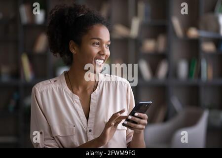 Happy young african american woman using smartphone. Stock Photo