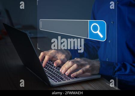 Searching on Internet with person using a browser software on laptop computer to open search engine with text bar and magnifying glass icon. Access in Stock Photo