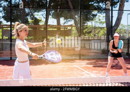 woman smashing in paddle tennis action. Training Basket balls in foreground Stock Photo