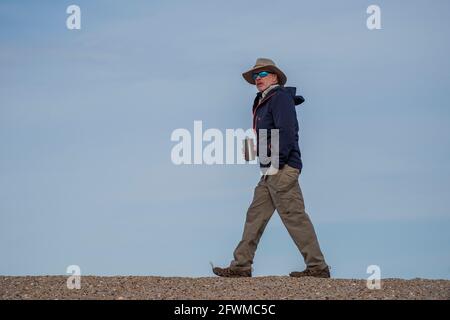 A man hikes atop a large sand dune at  assateague island national seashore. Stock Photo