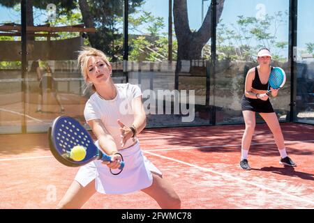 woman smashing in paddle tennis action. Training Basket balls in foreground Stock Photo