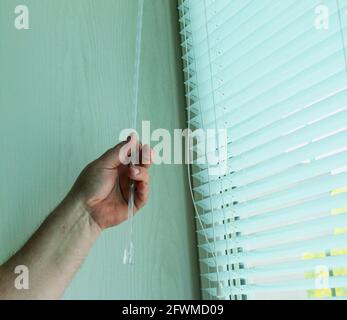 Window blinds installation process. Man testing cassette roller blinds on windows Stock Photo
