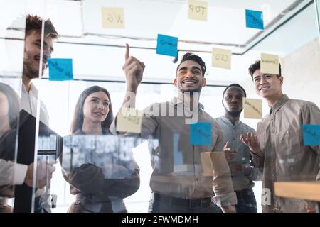 Colleagues having meeting using sticky notes on glass wall Stock Photo