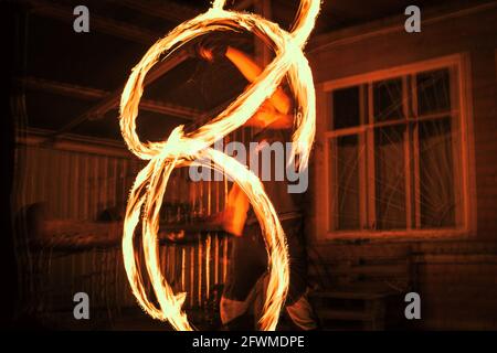 The spinning fire dancer performing burning fire poi dance Stock Photo