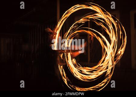 The spinning fire dancer performing burning fire poi dance Stock Photo