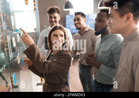 Colleagues having meeting using sticky notes on glass wall Stock Photo