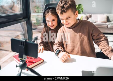 Brother and sister watching video on the phone.  Children study online at home Stock Photo