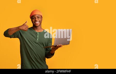 Remote Work Opportunities. Black hipster guy holding laptop and showing thumb up Stock Photo