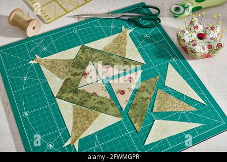 Pieces of fabric laid out in the shape of a patchwork block, sewing and quilting accessories. Stock Photo