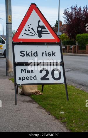 Road works, skid risk, re-surfacing, carriageway, stone chippings, grit, sweeper, roller, vehicle, skidding, red warning sign, 20mph, max speed, limit Stock Photo