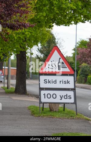 Road works, skid risk, re-surfacing, carriageway, stone chippings, grit, sweeper, roller, vehicle, skidding, red warning sign, 20mph, max speed, limit Stock Photo