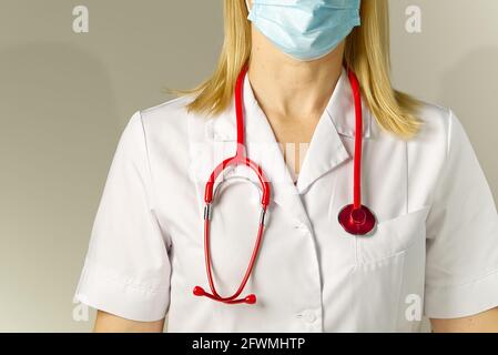 Doctor in medical protective mask and suit on beige background. No face. woman Stock Photo