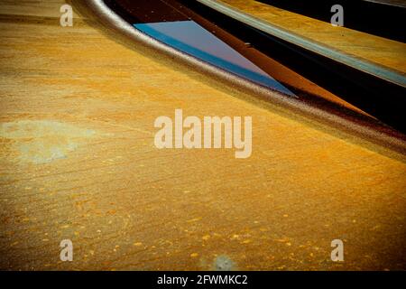 Abstract close-up of curved metallic and geometric forms against a weathered golden surface, creating dynamic lines, texture, contrast and design. Stock Photo