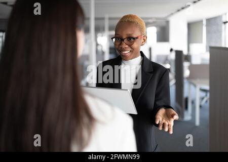 Optimistic black manager discussing project with colleague Stock Photo