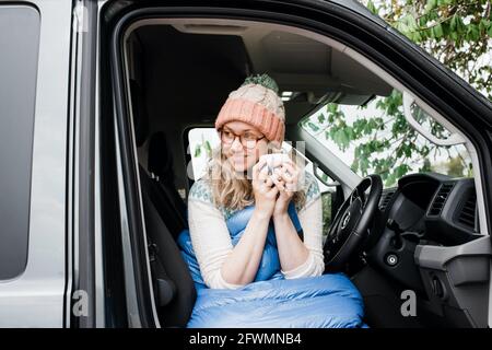 woman sat in her van drinking a cup of coffee enjoying the morning Stock Photo