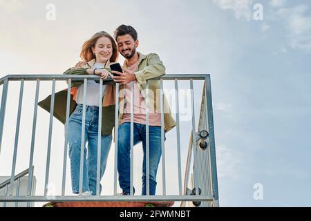Young multiracial couple smiles while they are looking at a phone Stock Photo
