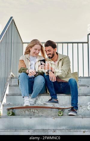 Young multiracial couple smiles while they are looking at a phone Stock Photo