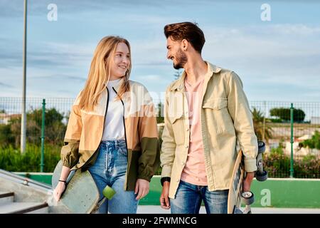 A young couple looks at each other and smiles while holding a skate Stock Photo