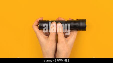 Banner hand hold flashlight on office desk yellow orange background, top view, workspace concept with copy space Stock Photo
