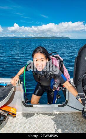 diver climbing back into dingy after a successful dive in Raja Ampat Stock Photo