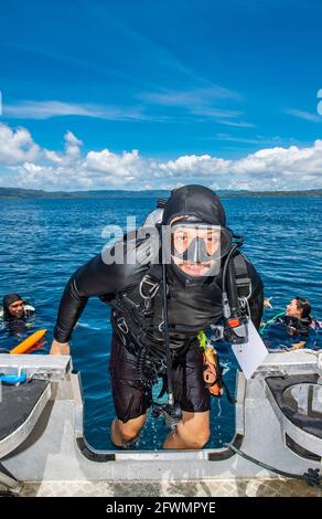 diver climbing back into dingy after a successful dive in Raja Ampat Stock Photo