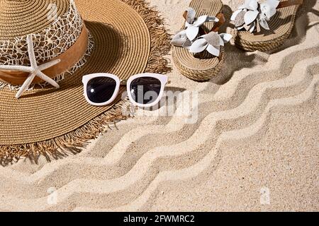 Large round brown summer heat, white sunglasses, sandals and starfish on nice beach sand, top view, copy space Stock Photo