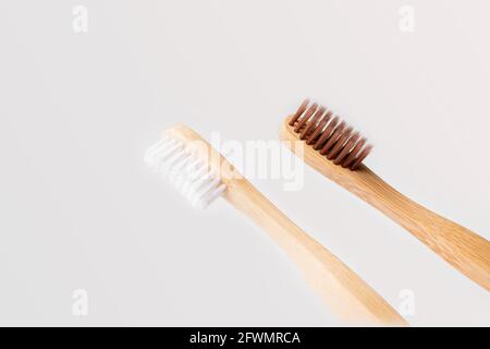two diagonal wooden toothbrushes one with white bristles and the other brown on light background Stock Photo