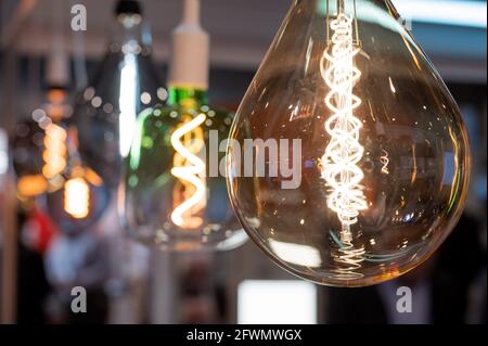 Many differently shaped incandescent bulbs are suspended in the dark Stock Photo