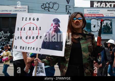 A demonstrator holds a sign against police brutality that reads 'I have a bullet where do you want it?' as clashes and riots evolve in Medellin, Colombia after demonstrators and riot police (ESMAD) during a demonstration that escalated to clashes after security cameras and commerce were affected by the protest. In Medellin, Antioquia, Colombia on 22, 2021. Stock Photo