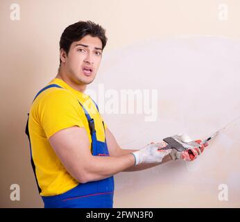 The young contractor employee applying plaster on wall Stock Photo