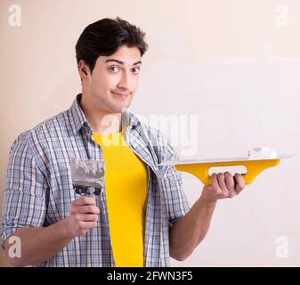 The young man applying plaster on wall at home Stock Photo