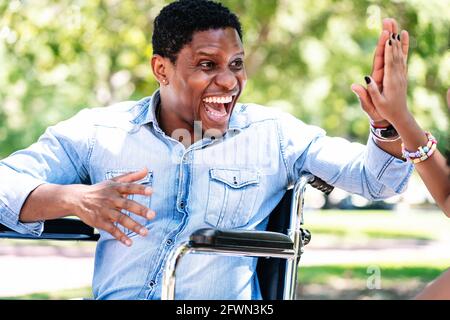 Man in a wheelchair at the park with his daughter. Stock Photo