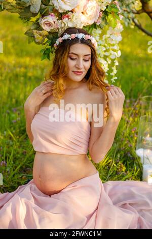 Pretty young pregnant woman relaxing outside in nature at summer day. Stock Photo