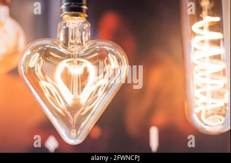 Many differently shaped incandescent bulbs are suspended in the dark Stock Photo