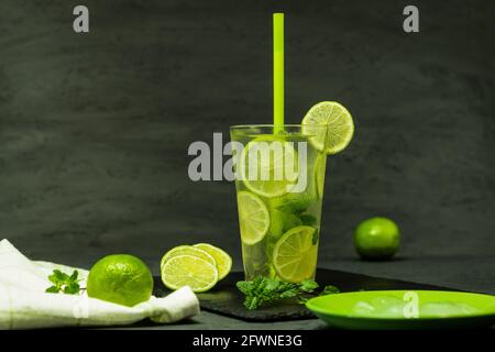 Cool drink with lime, ice and mint. Homemade refreshing lemonade, background with space for text. Mojito cocktail on black background with ice cubes Stock Photo