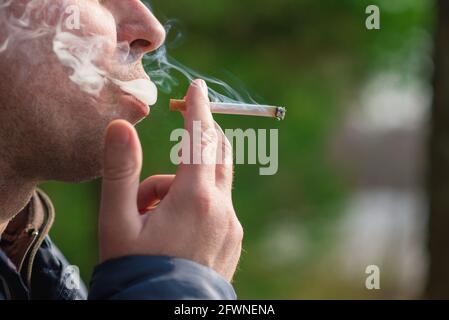 Cropped close up man smoking cigarette outdoors shot. Stock Photo