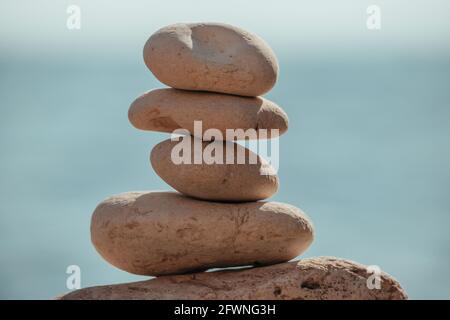 Pyramid stones on the seashore on a sunny day on the blue sea background. Happy holidays. Pebble beach, calm sea, travel destination. Concept of happy Stock Photo