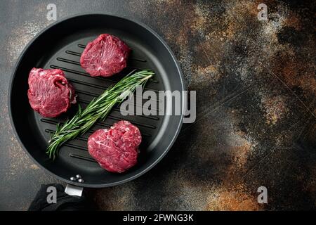 Raw beef fillet steaks with spices and whole marbled tenderloin cut set, in cast iron frying pan, on old dark rustic background, top view flat lay, wi Stock Photo