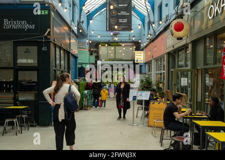 Brixton, London- May 2021: Inside Brixton Village which is part of Brixton Market- an indoor hall of world food stalls, bars and shops. Stock Photo