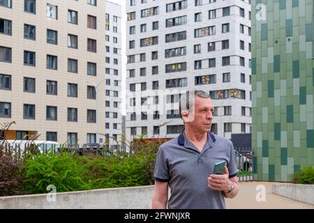 An adult caucasian man stands and holds a smartphone Stock Photo